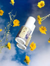 Saffron Glow Dropping Serum by Raafiaura surrounded by yellow flowers against a blue sky backdrop